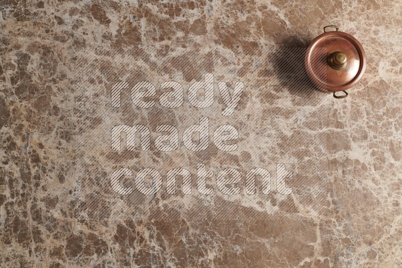 A small copper pot on beige marble background