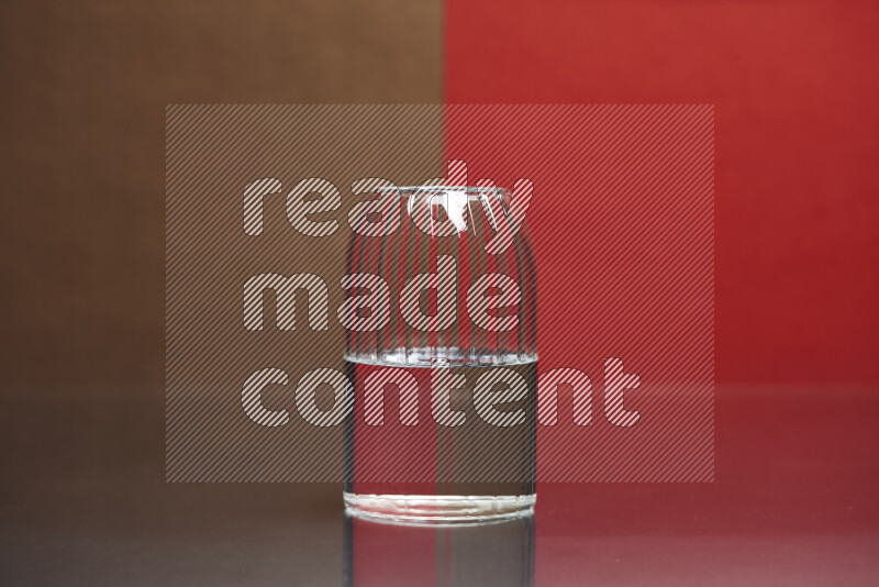 The image features a clear glassware filled with water, set against brown and red background