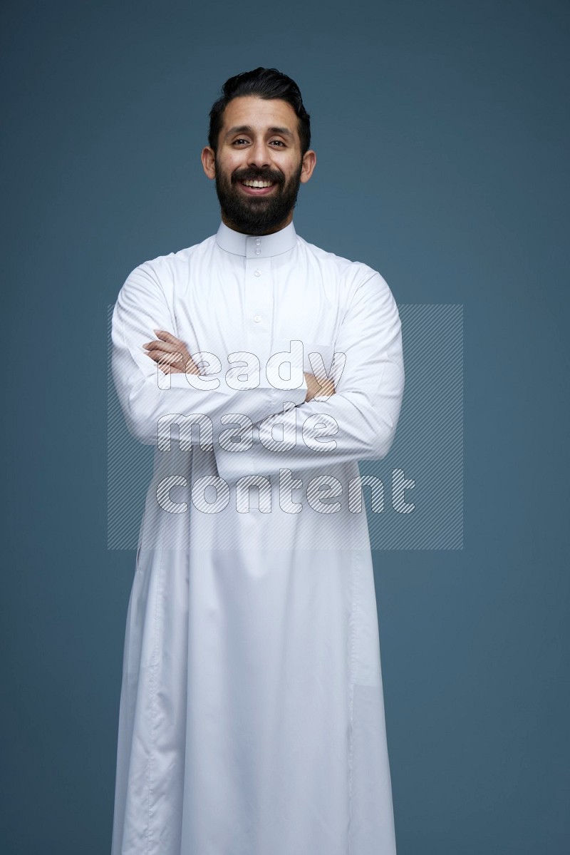 A man posing in a blue background wearing Saudi Thob