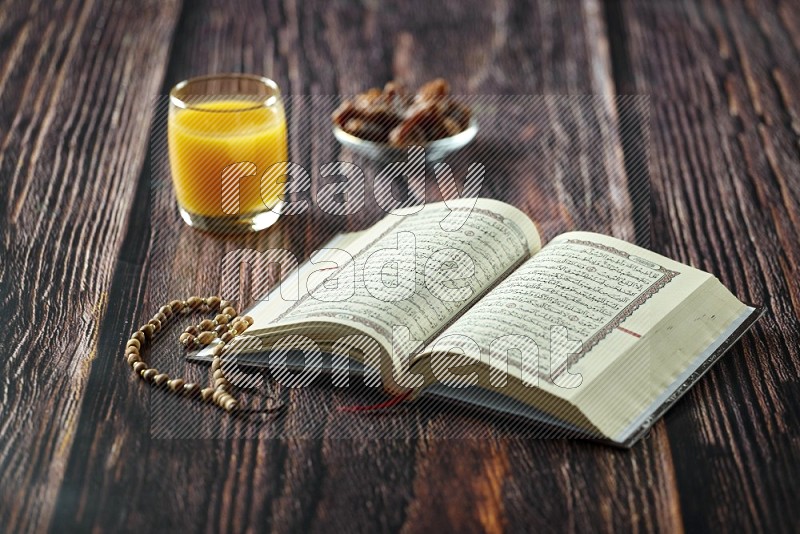 Quran with dates, prayer beads and different drinks all placed on wooden background