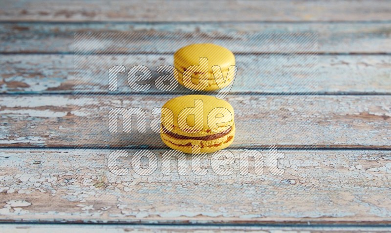 45º Shot of two Yellow Lemon macarons on light blue wooden background