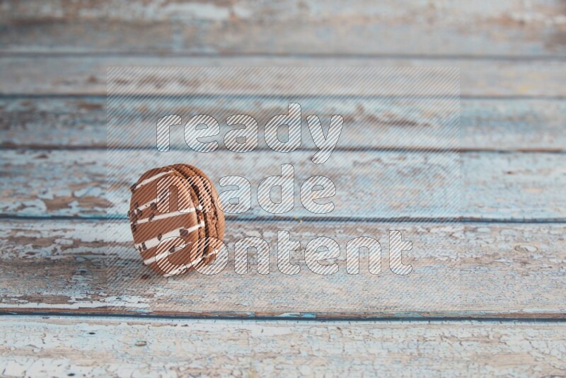 45º Shot of Brown white Chocolate Caramel macaron on light blue wooden background
