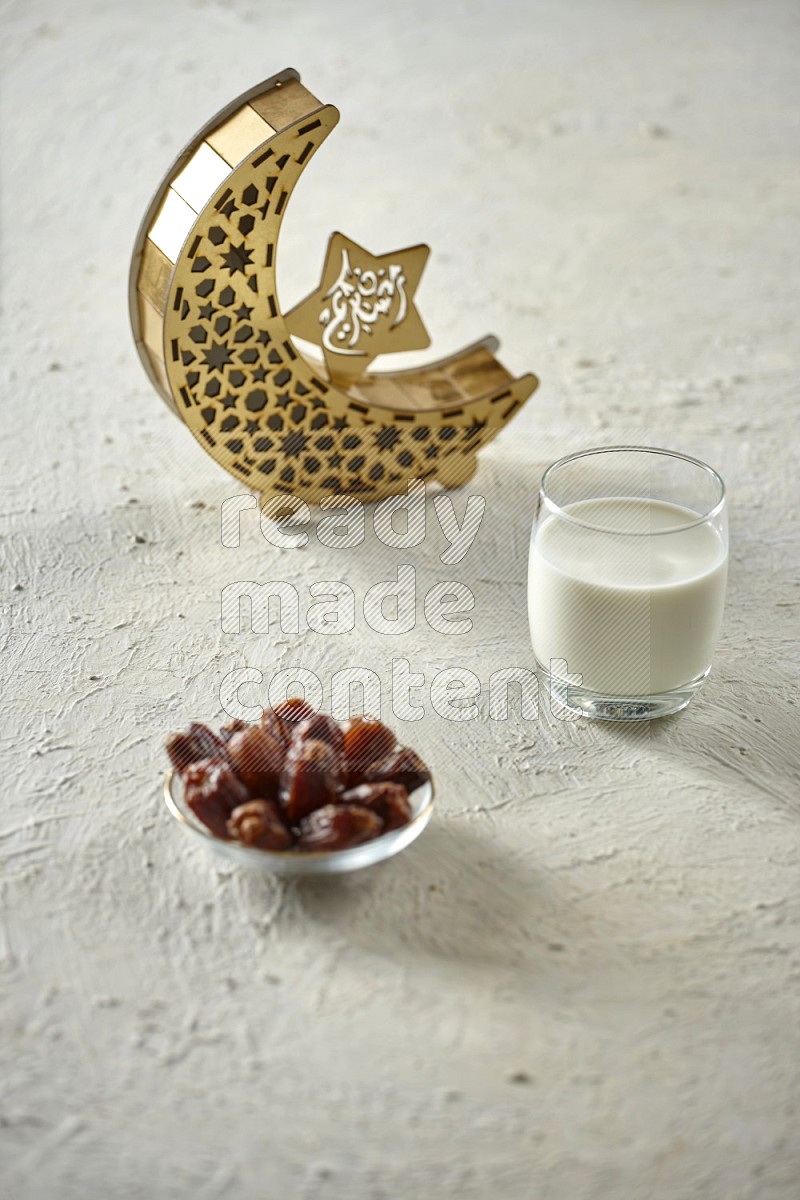 A wooden golden crescent lantern with different drinks, dates, nuts, prayer beads and quran on white background