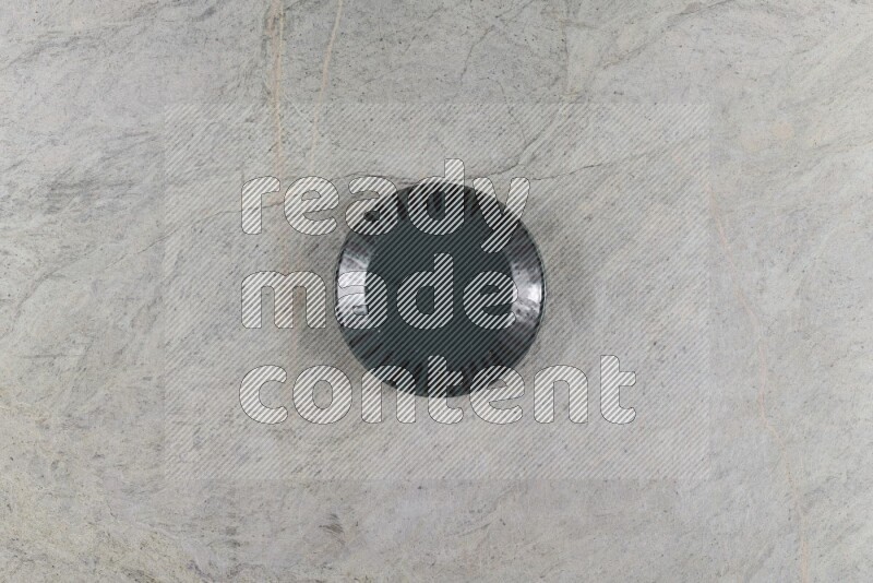 A dark green pottery plate on grey marble background