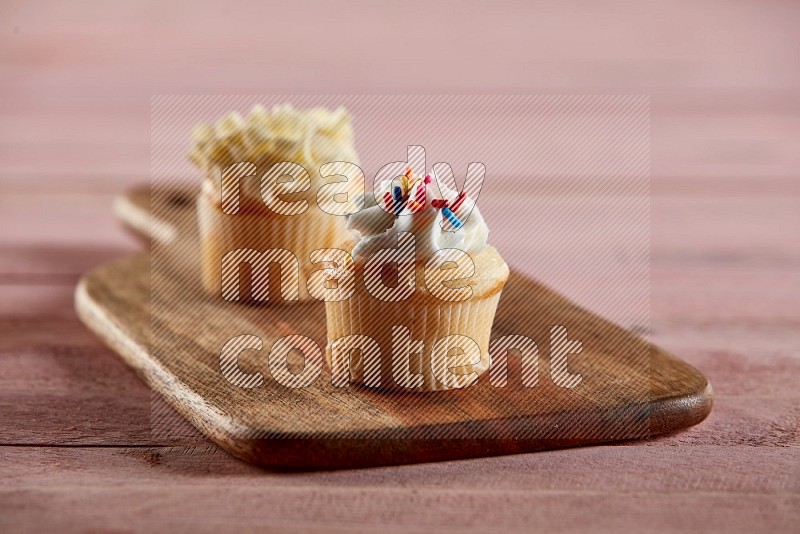 Vanilla mini cupcake topped with cream on a wooden board