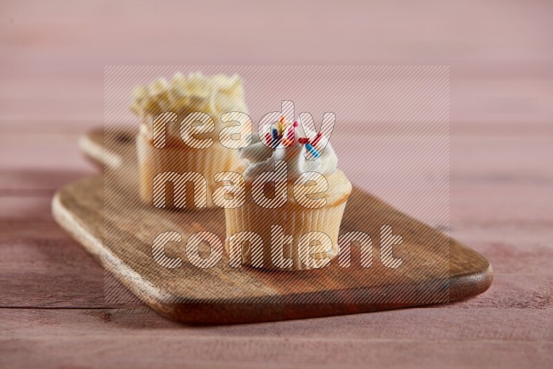 Vanilla mini cupcake topped with cream on a wooden board