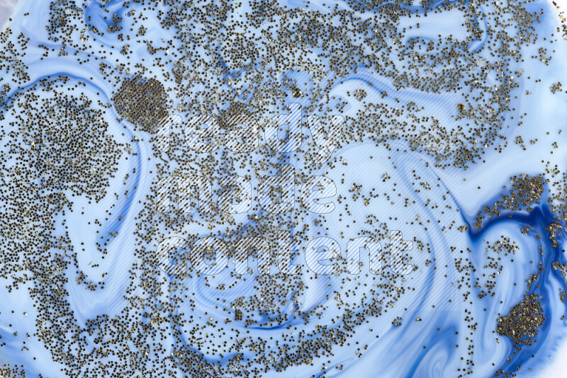 لقطة مقربة لبريق ذهبي متلألئ منتشر على خلفية من اللون الأزرق في حركات دائرية