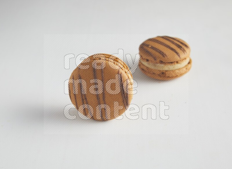 45º Shot of two light brown  Almond Cream macarons on white background