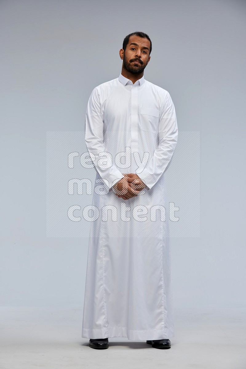 Saudi man Wearing Thob standing interacting with the camera on Gray background