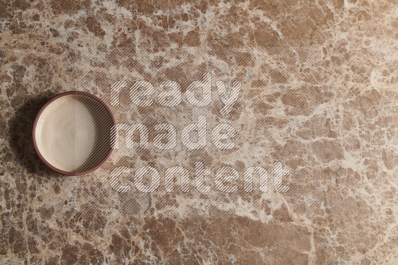 A beige pottery oven plate on beige marble background