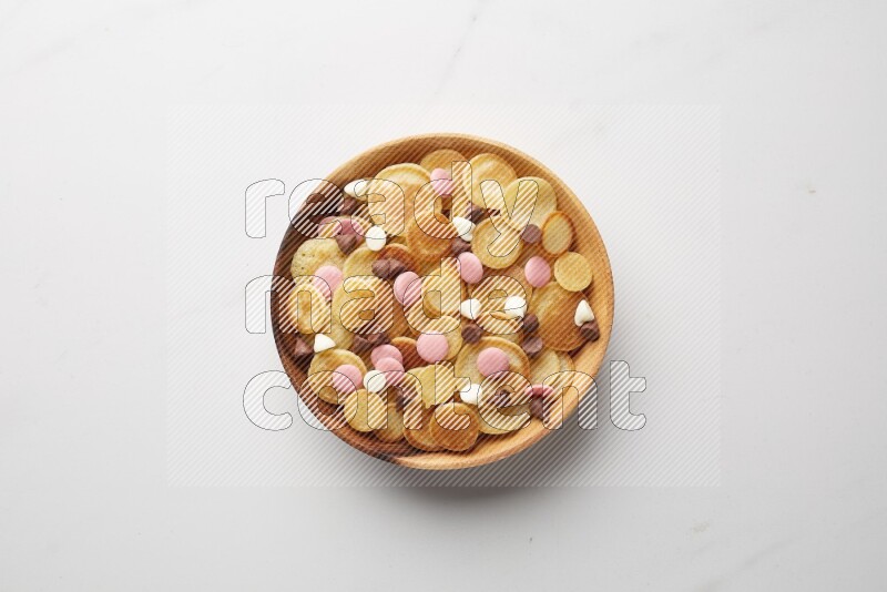 Top-view shot of mixed chocolate chips cereal pancakes in a round bowl on white background
