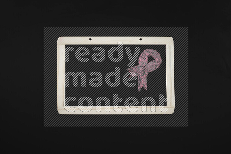 A drawing of pink ribbon on blackboard on black background