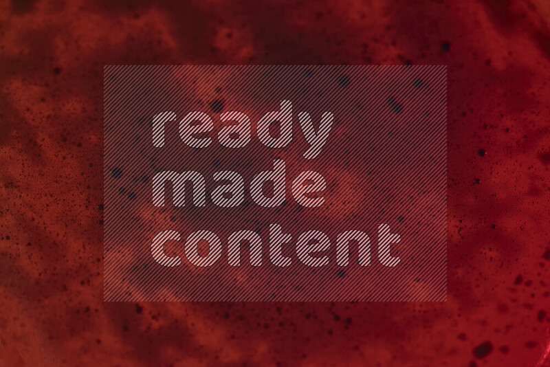 لقطات مقربة لقطرات ألوان مائية زرقاء على سطح الزيت على خلفية حمراء