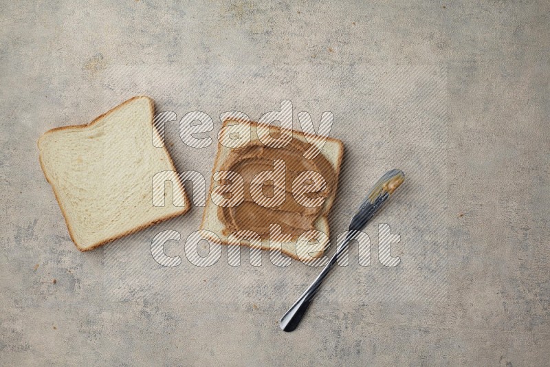 Creamy peanut butter on white toast and white toast slices on a light blue textured background