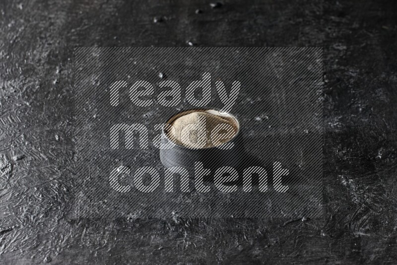 وعاء فخار أسود مملوء ببودرة الفلفل الأبيض على أرضية سوداء