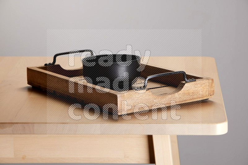 black bowl on a light colored rectangular wooden tray with handles