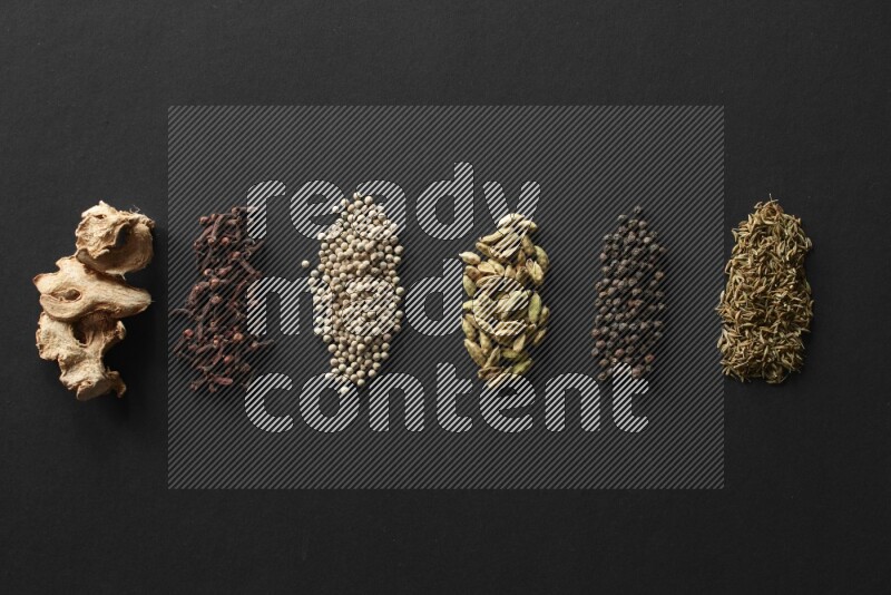 ginger, cloves, white pepper, cardamom, black pepper and Cumin lined on a Black background