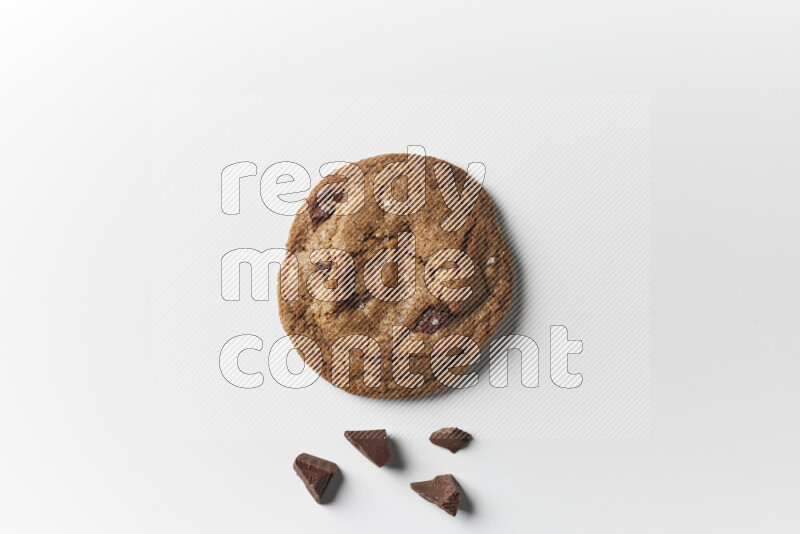 A single chocolate chips cookie with chocolate beside it on a white background