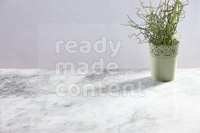 Artificial plant in green decorative pot on grey marble background
