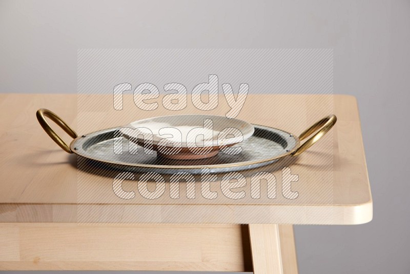 multicolored plate placed on a rounded stainless steel tray with golden handels on the edge of wooden table