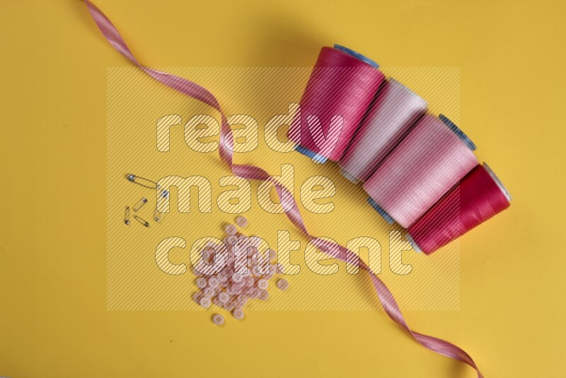 A pink collection of sewing and tailoring tools arranged on a yellow background