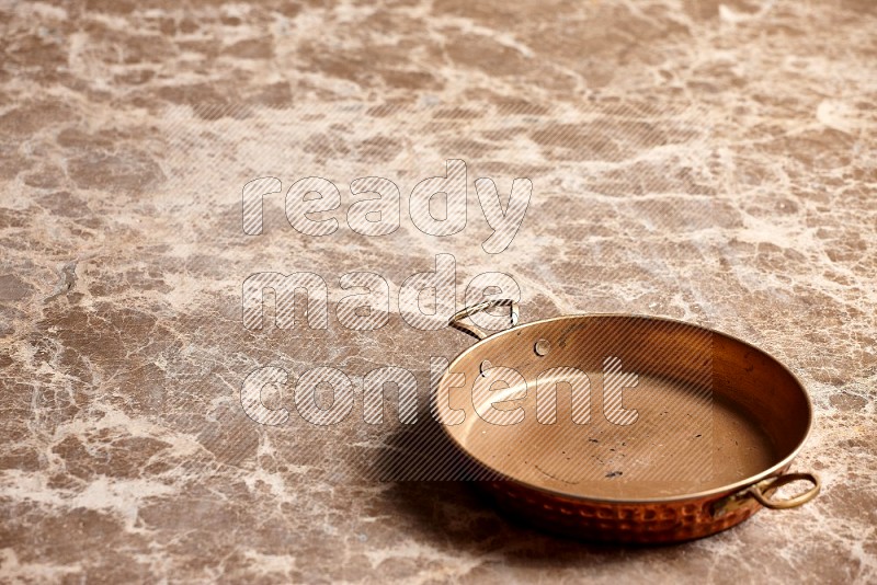 Small Copper Pan on Beige Marble Flooring, 45 degrees