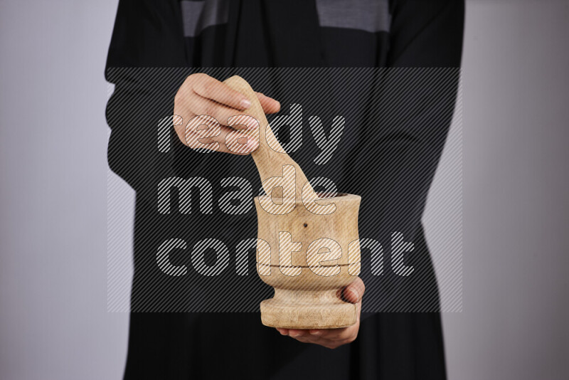 A woman in black abaya holding different wooden essentials in different positions