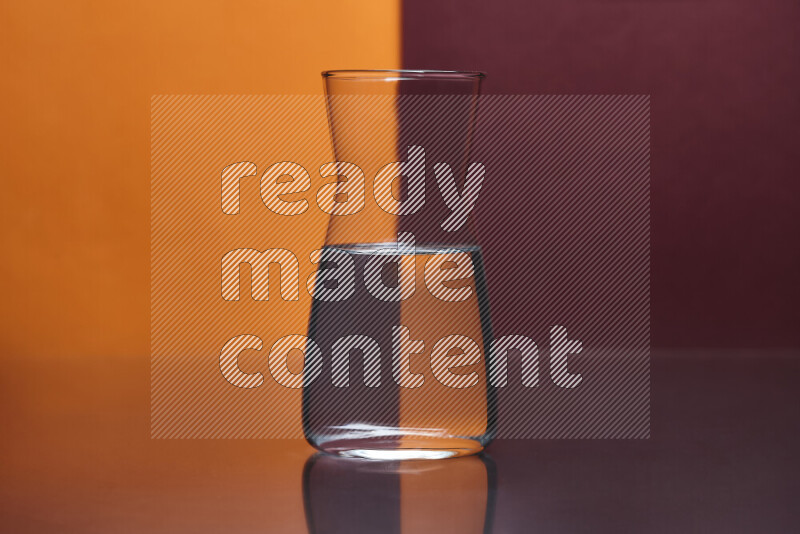 The image features a clear glassware filled with water, set against orange and dark red background