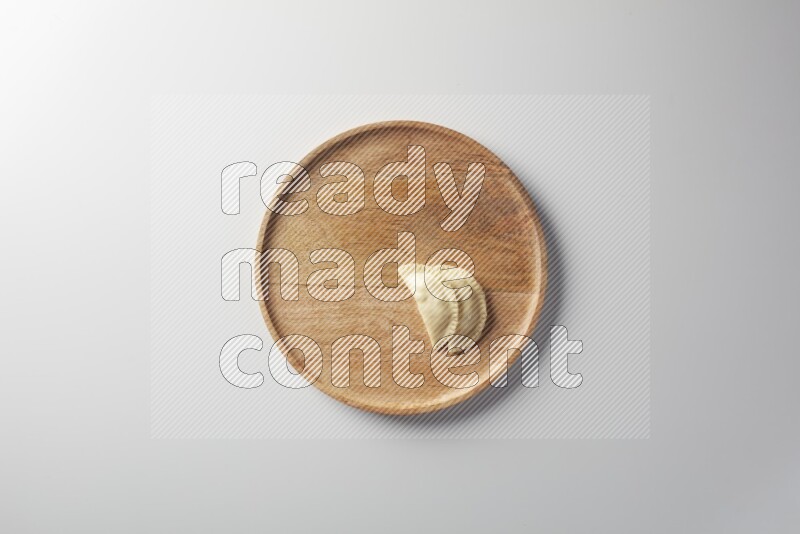 Two Sambosas on a wooden round plate on a white background