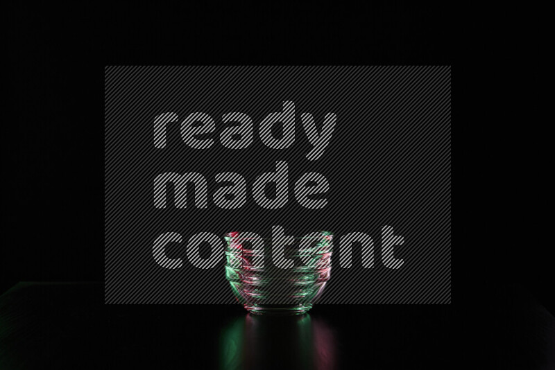 Glassware with rim light in red and green against black background