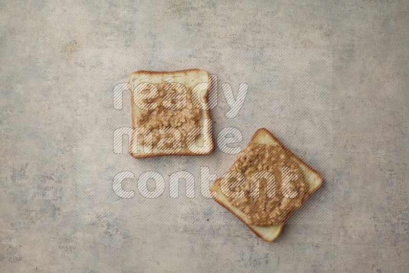 Crunchy peanut butter on a toasted white toast slices on a light blue textured background