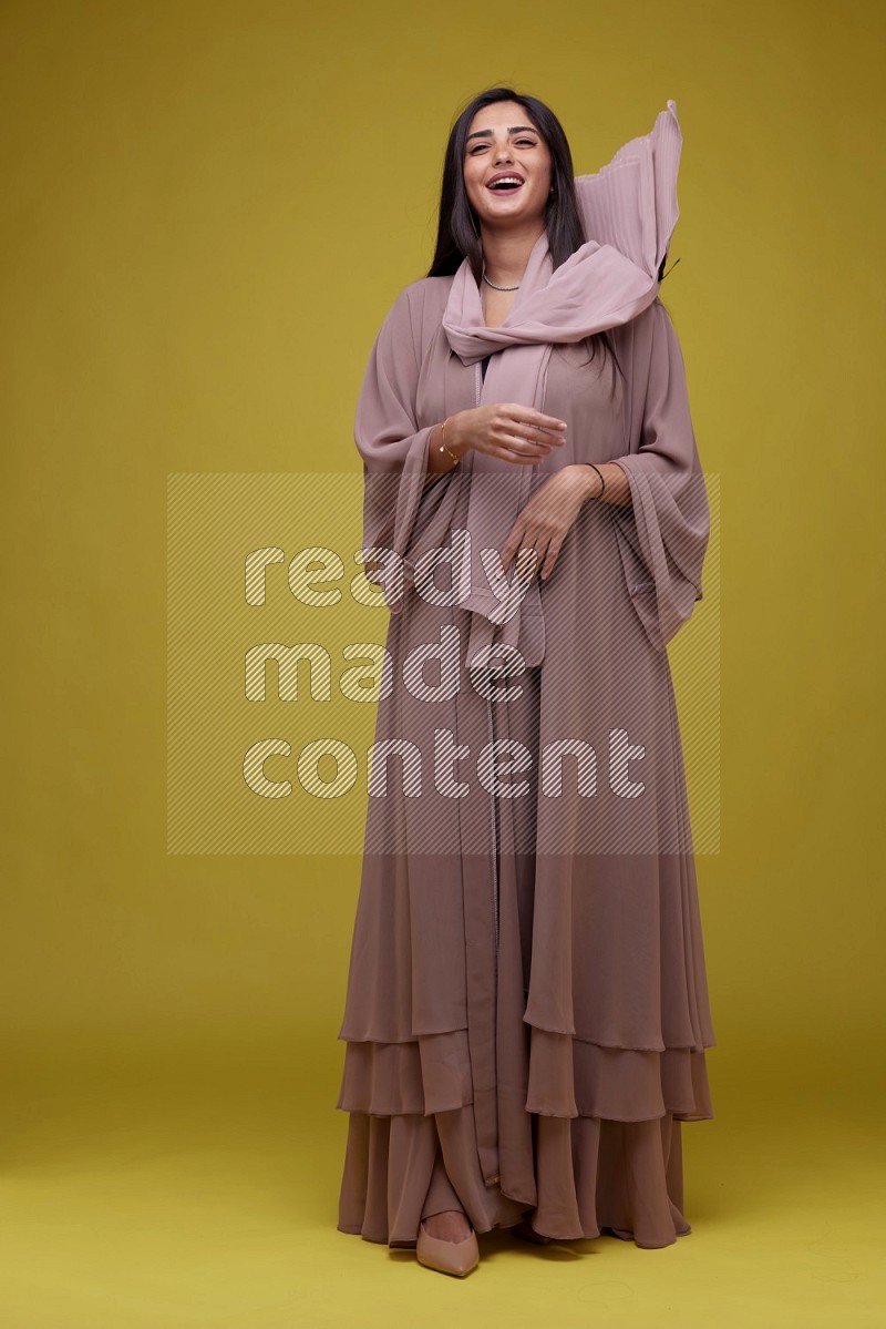 A woman Posing on a Yellow Background wearing Brown Abaya