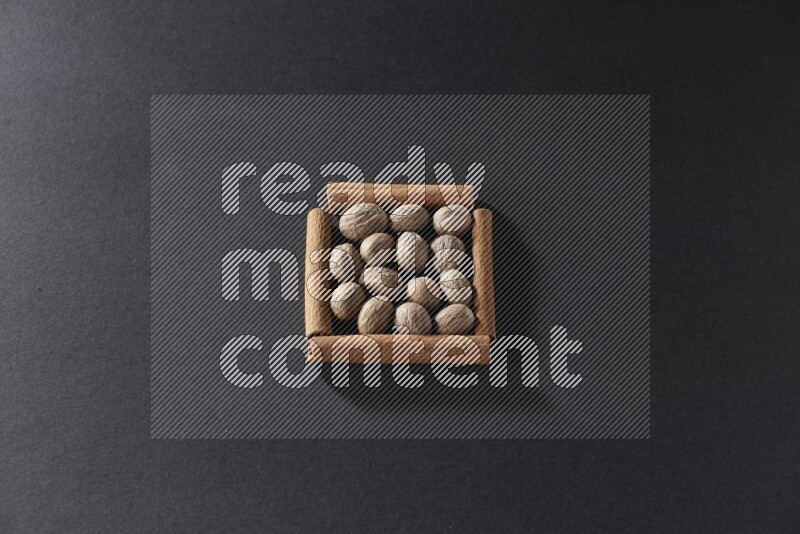 أربعة من أعواد القرفة مكونة شكل مربع بداخلها جوزة الطيب علي خلفية سوداء