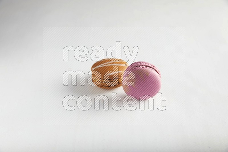 45º Shot of of two assorted Brown Irish Cream, and Purple Strawberry macarons on white background