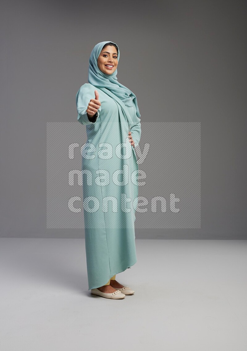 Saudi Woman wearing Abaya standing interacting with the camera on Gray background