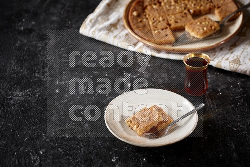 Basbousa with tea in a dark setup