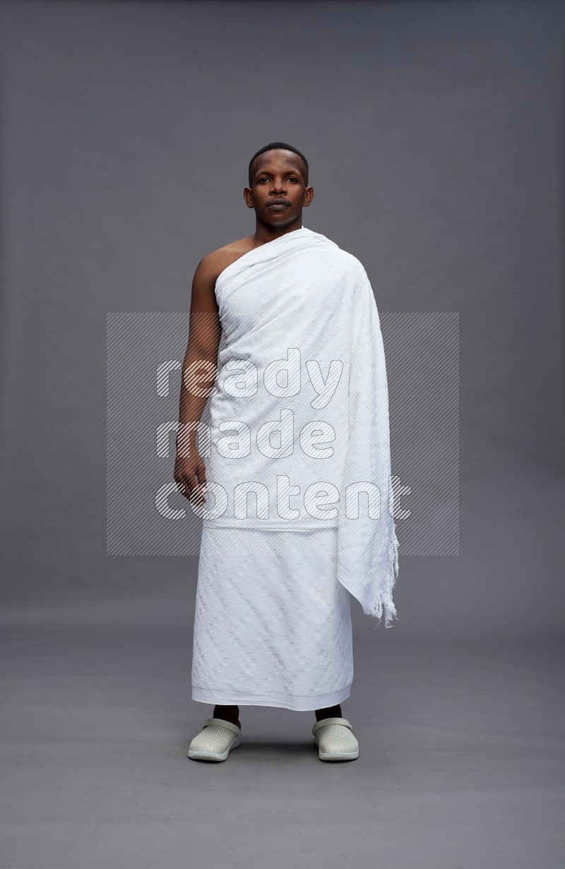 A man wearing Ehram Standing Interacting with the camera on gray background