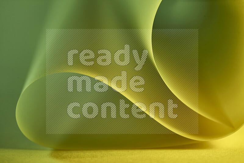 An abstract art piece displaying smooth curves in green and yellow gradients created by colored light