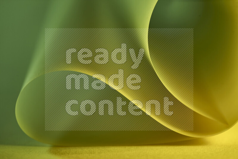 An abstract art piece displaying smooth curves in green and yellow gradients created by colored light