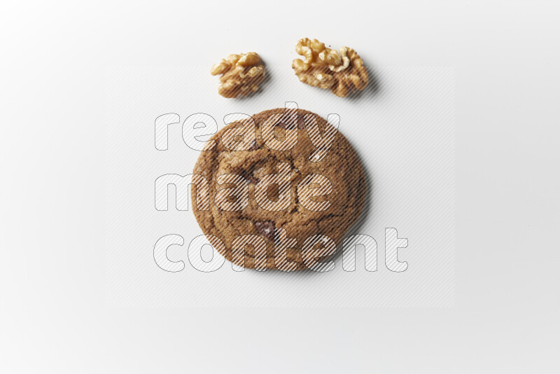 A single chocolate chips cookie with walnuts beside it on a white background