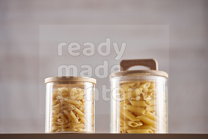 Raw pasta in glass jars on beige background