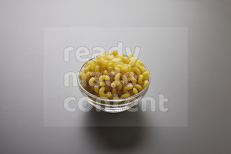 Twist pasta in a glass bowl on grey background