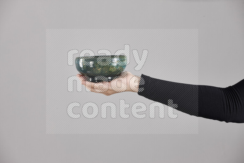 A woman in black abaya holding different pottery essentials in different positions