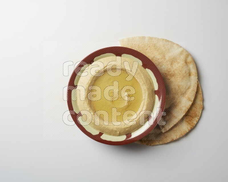 Hummus in a traditional plate garnished with olive oil on a white background