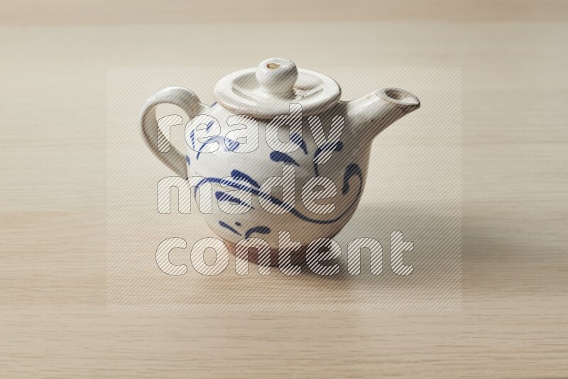 A pottery teapot on light wooden background
