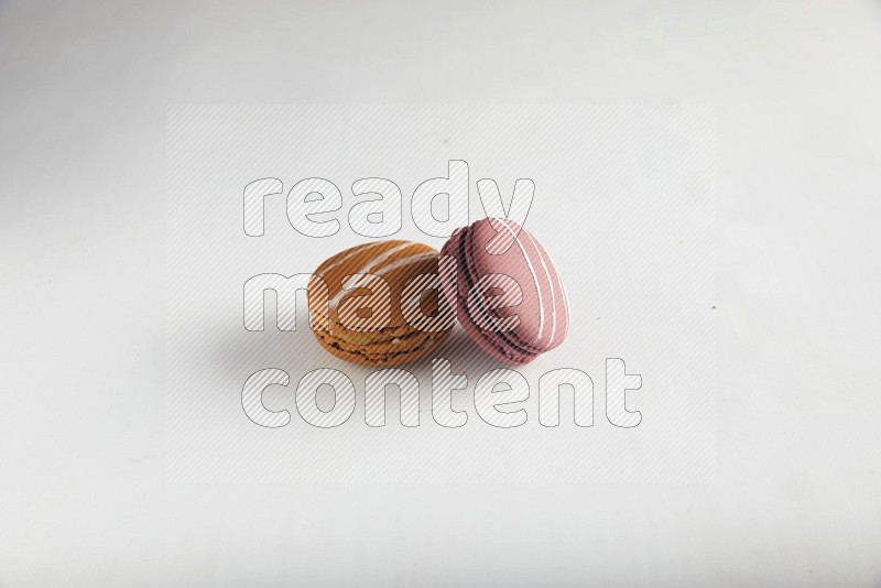 45º Shot of of two assorted Brown Irish Cream, and Red Poppy Flower macarons on white background