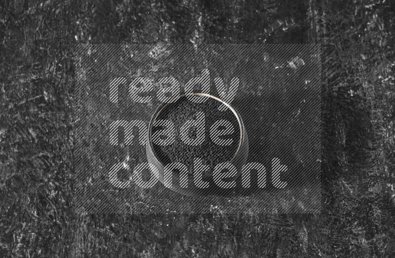 وعاء فخاري أسود ممتلئ ببذور حبة البركة علي خلفية سوداء