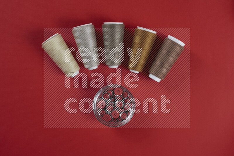 A brown and red collection of sewing and tailoring tools arranged on a red background