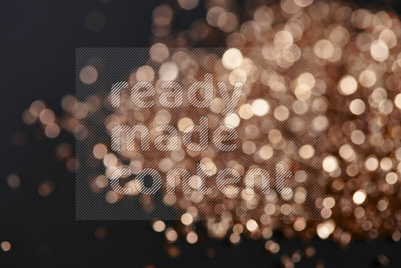 Bronze shimmering fragments of glass scattered on a black background