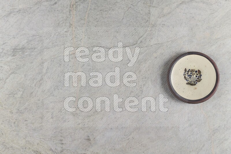 A decorative pottery plate on grey marble background